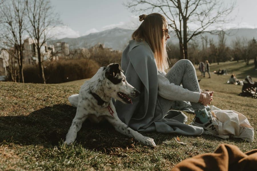 A woman relaxing in the park beside her happy dog